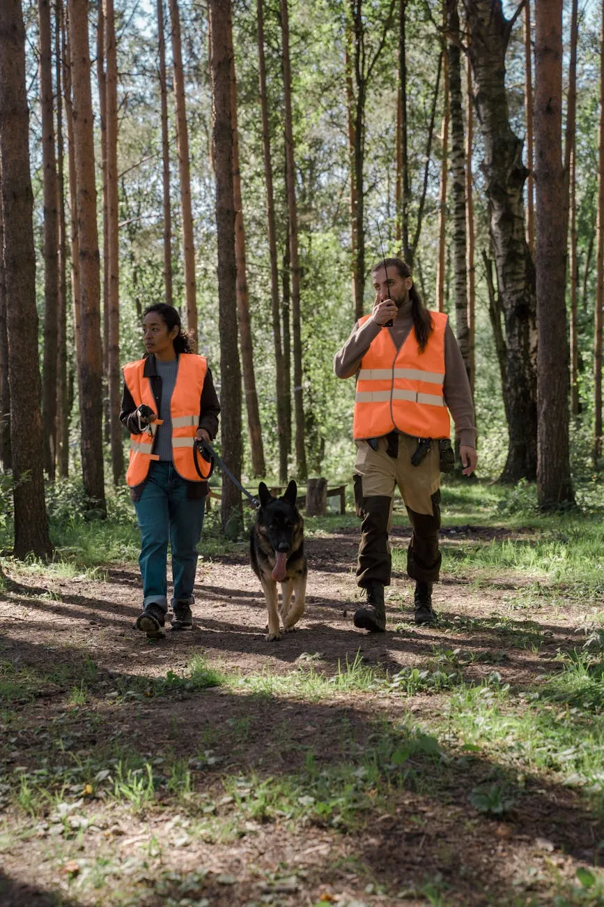 Two volunteers in safety vests walking a trail with a dog